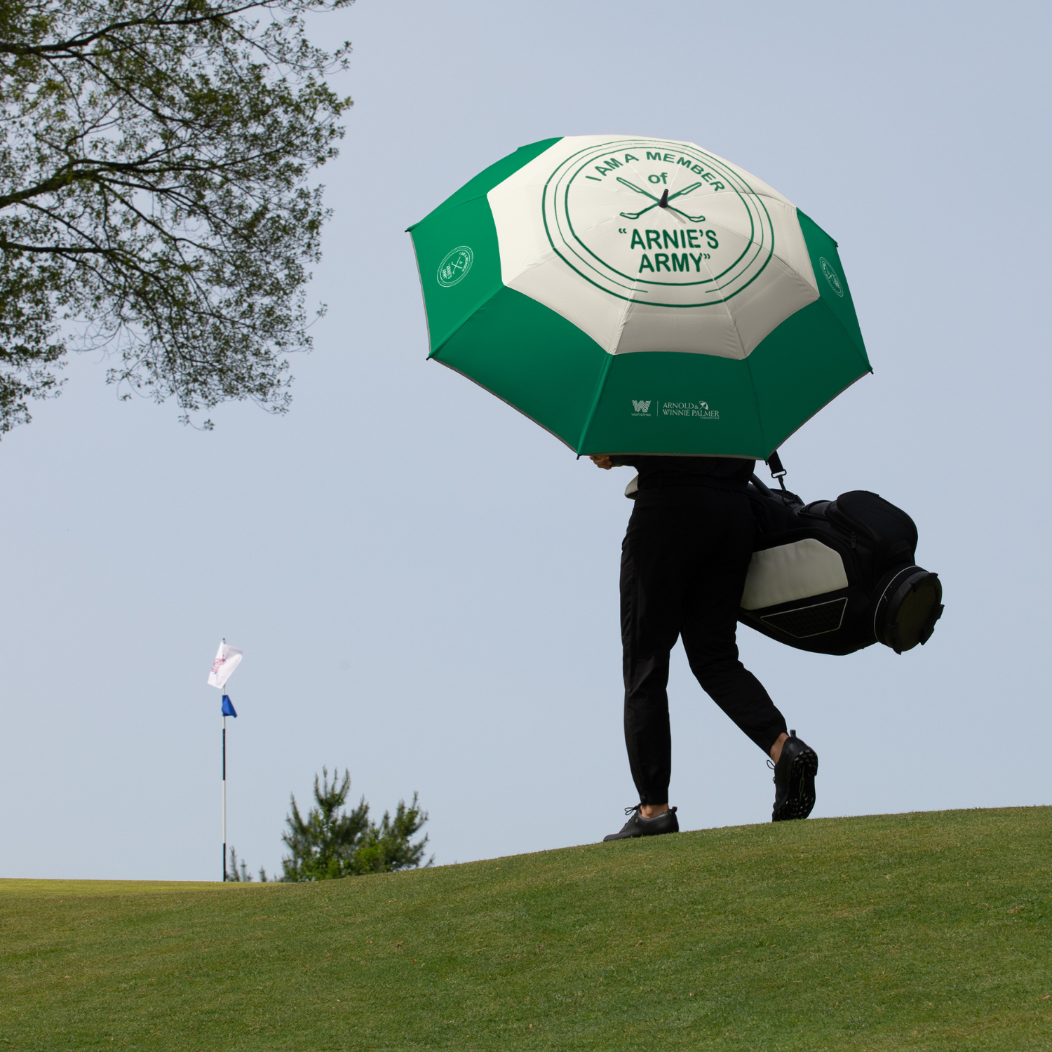 Man walking on golf course with Weatherman Golf Lite Umbrella in Arnold Palmer Arnie's Army design.