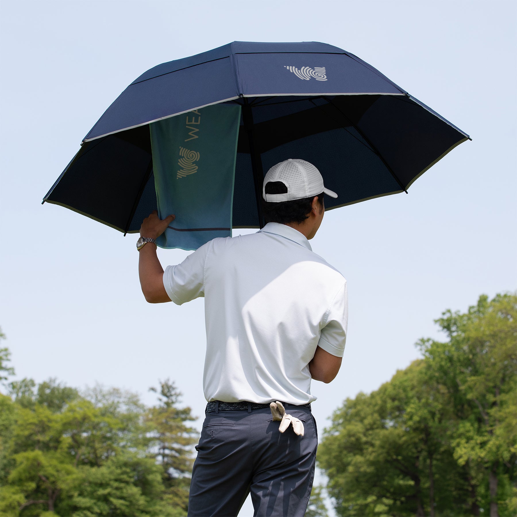 Man hanging Weatherman Golf Towel on Golf Lite Umbrella in navy.