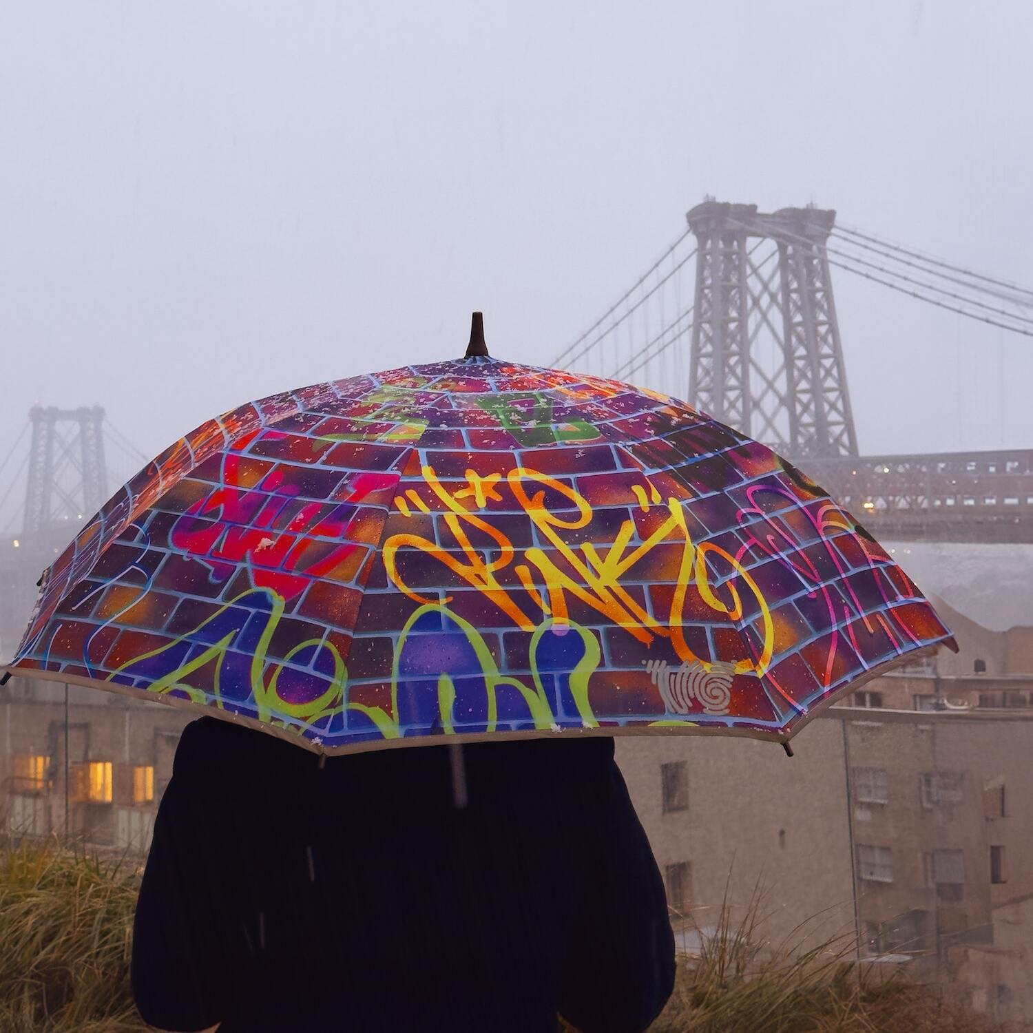 A man holding an umbrella with a combination of pink, blue, and yellow colors