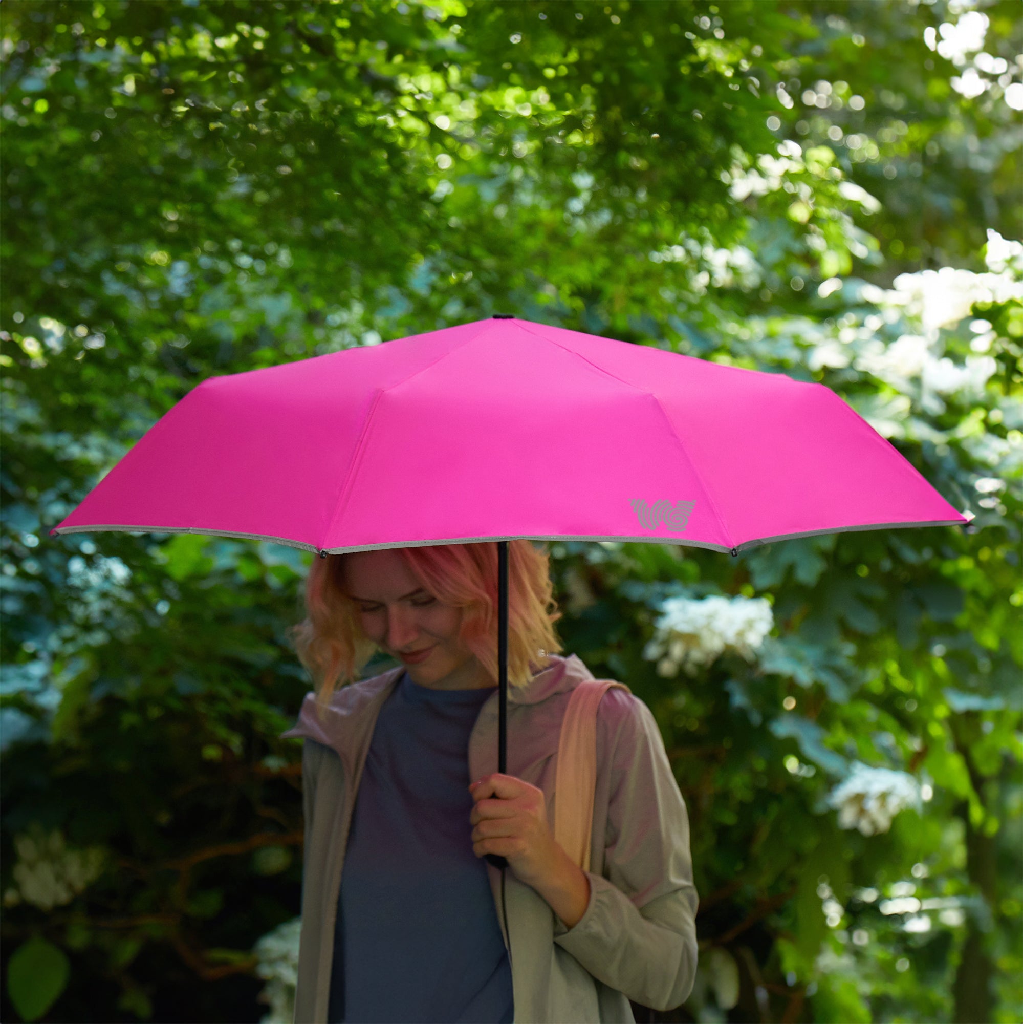 Woman walking with opened Weatherman Travel Umbrella in neon pink.
