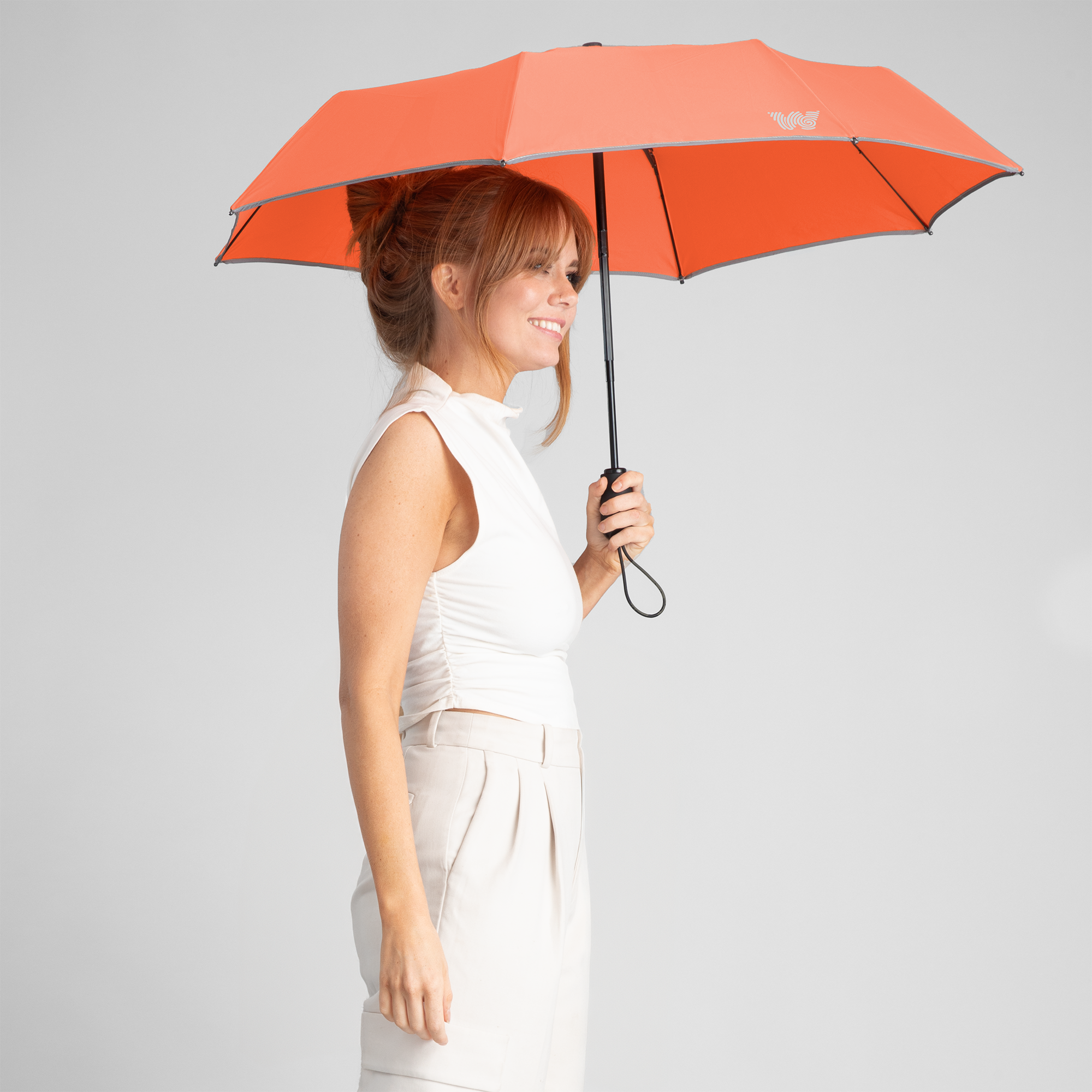 Woman walking with opened Weatherman Travel Umbrella in orange.