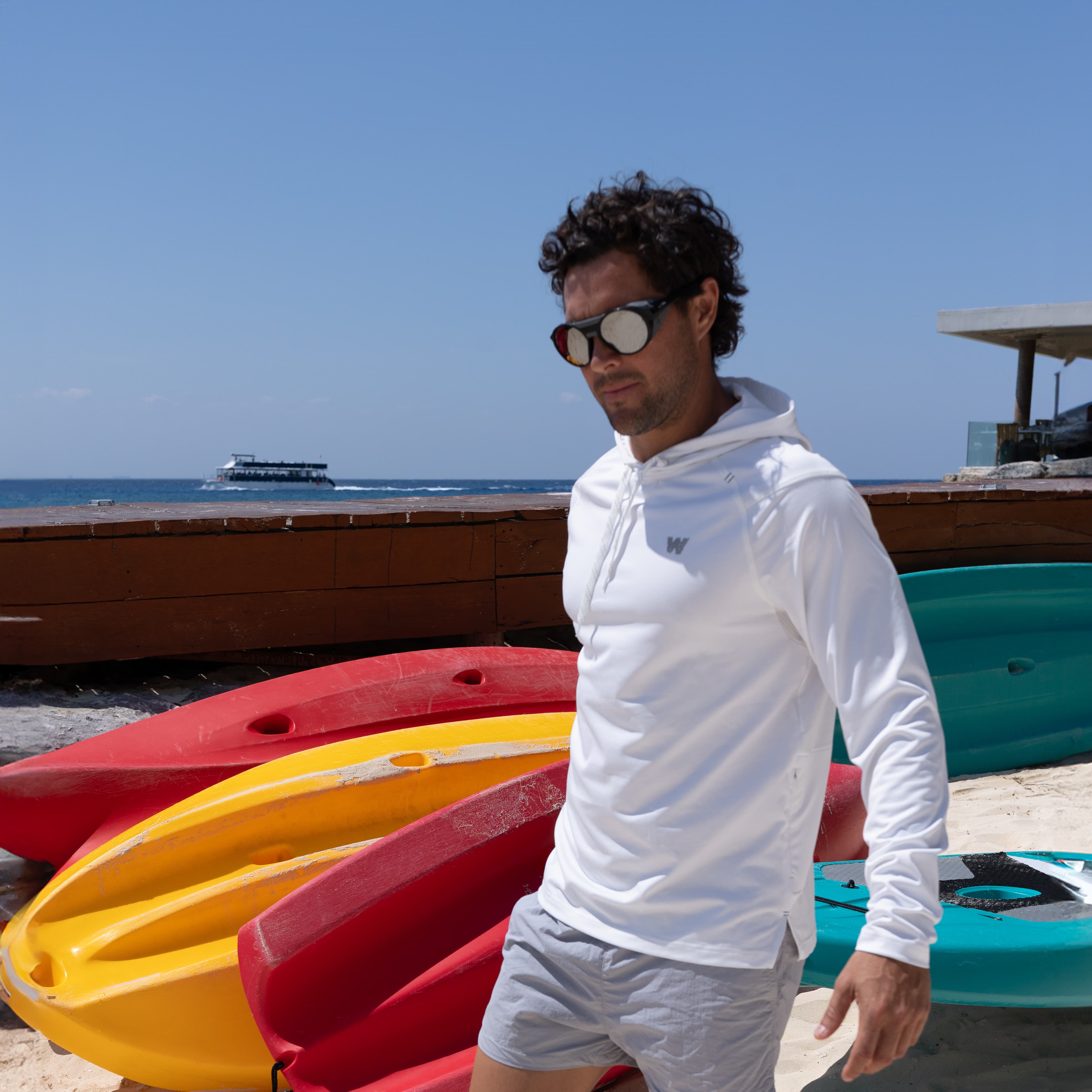 A man in a white shirt standing near a boats