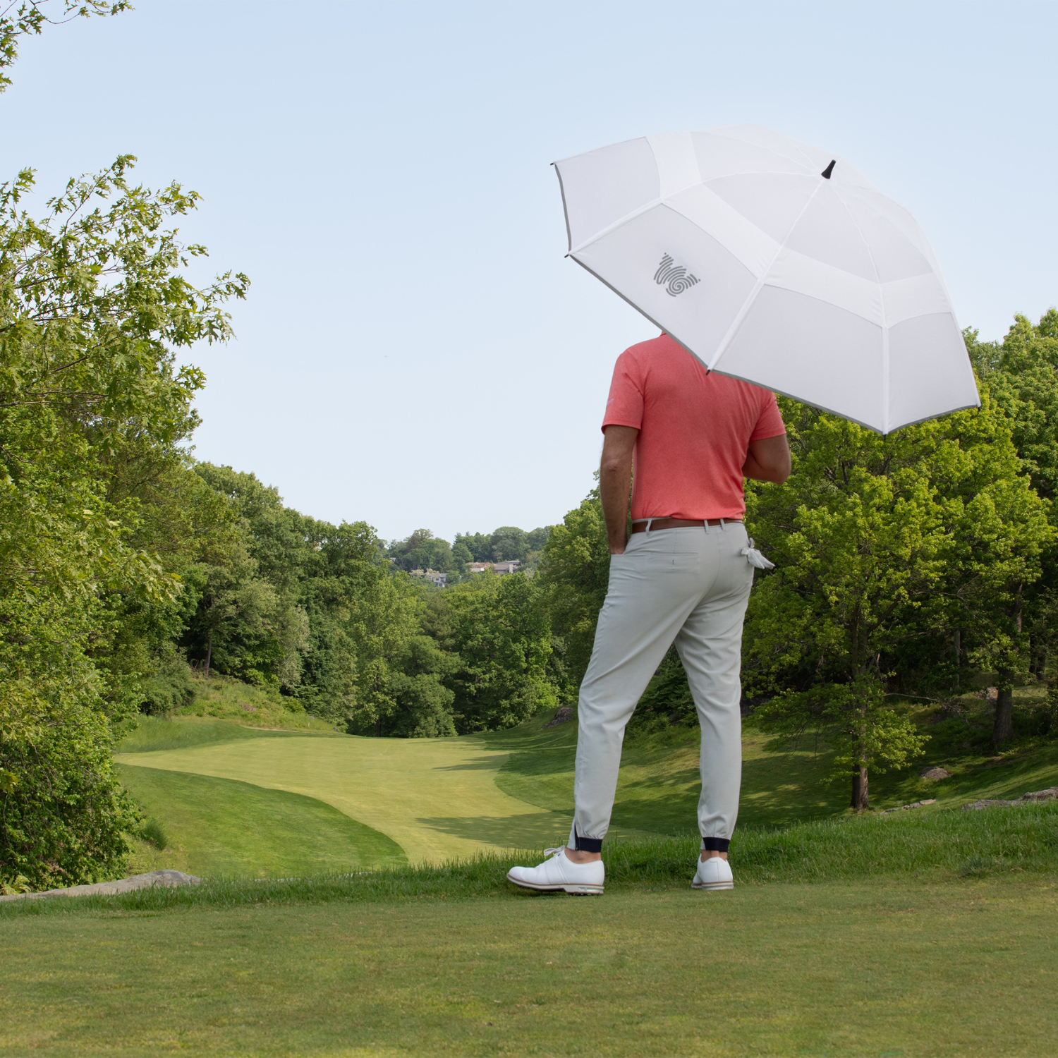 Man on golf course with Weatherman Golf Lite Umbrella in white.