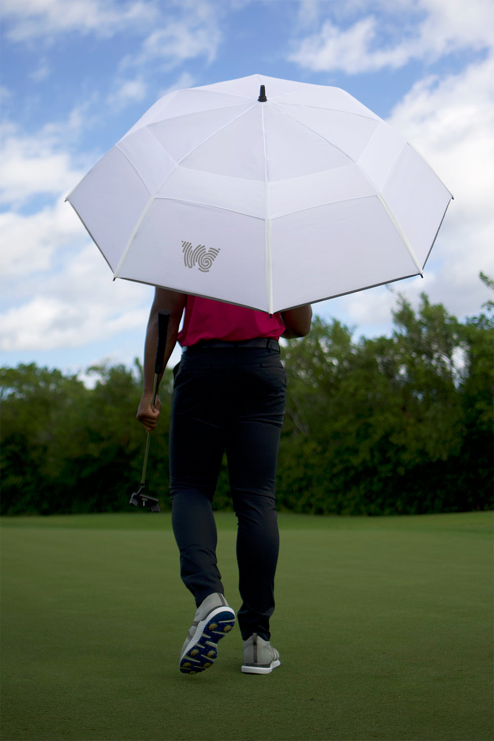 Man walking on golf course with Weatherman Golf Lite Umbrella in white.