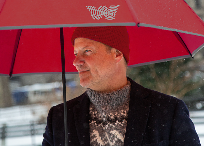 Founder Rick Reichmuth walking outside in the winter with a Weatherman Stick Umbrella in red.