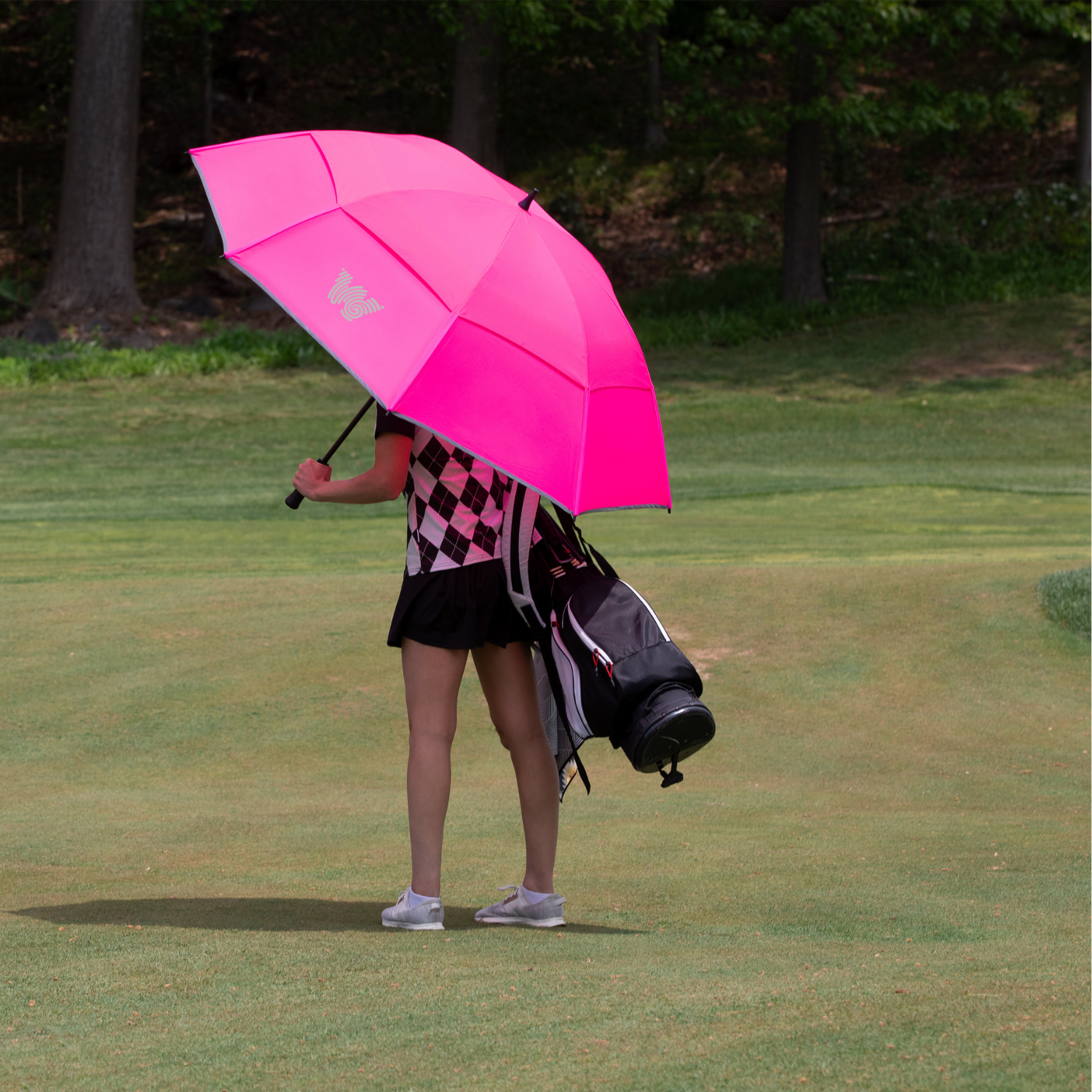 Woman walking on golf course with Weatherman Golf Lite Umbrella in pink.